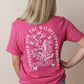 Person wearing a pink t-shirt with a Christian floral design and text on the back, with the phrase CONSIDER HOW THE WILDFLOWERS GROW
