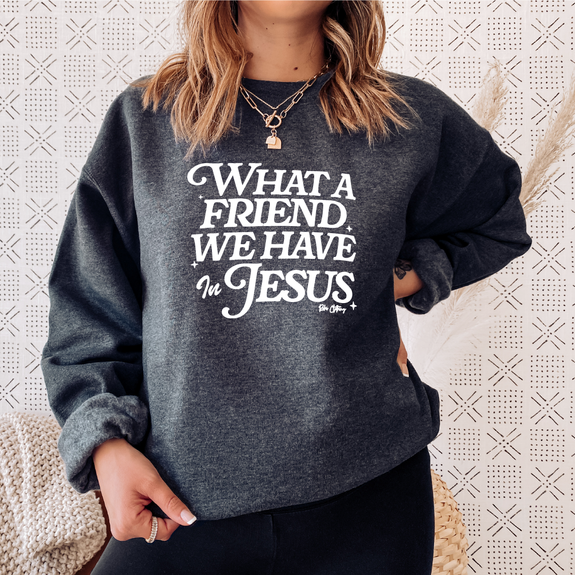 Charcoal gray Christian sweatshirt on a female model with white text that says "What A Friend We Have In Jesus" by Rohi Clothing